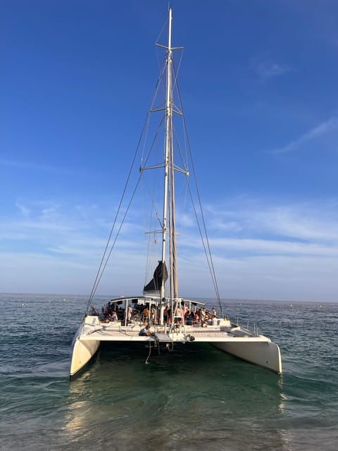Lloret de Mar: Sunset Catamaran Cruise with DJ and Drinks - Boarding the Catamaran Sensation: DJ Energy and Group Size