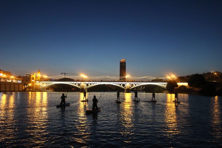 Seville: Sunset and Evening Paddle Boarding Tour - Passing Puente de Triana and the skyline from the Guadalquivir